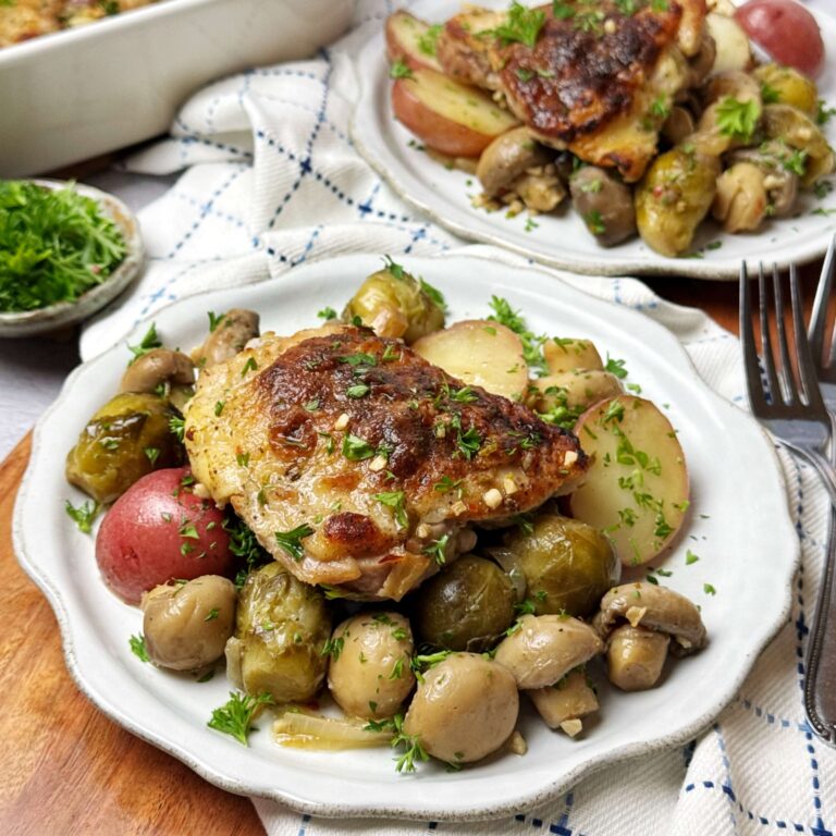 Crispy Chicken Thighs with Marinated Mushrooms and Potatoes on a white dinner plate.