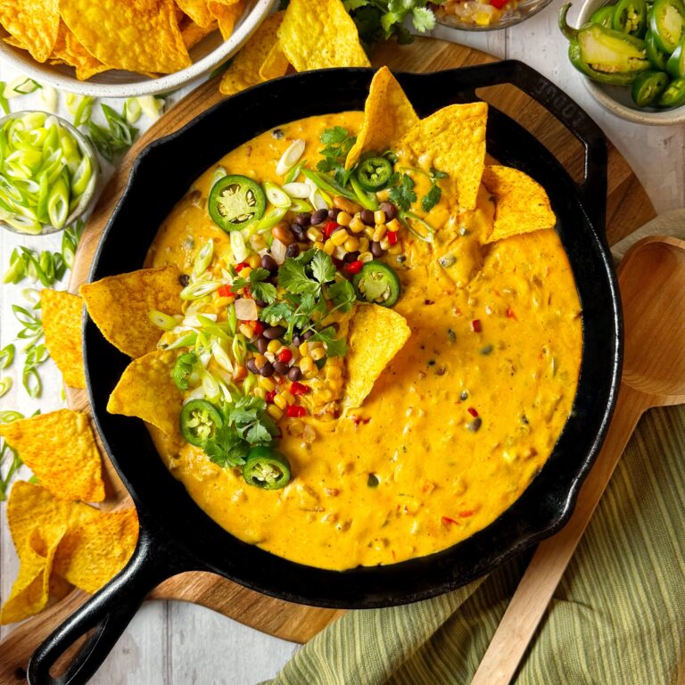 A black cast iron skillet with Cowboy Caviar Skillet Queso and chips