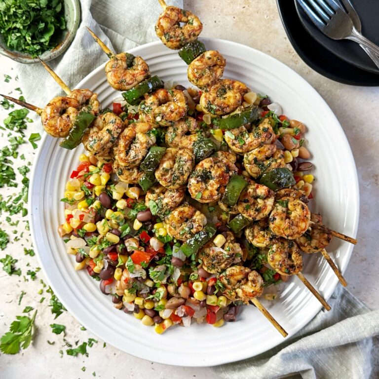 Marinated Grilled Shrimp on Skewers with Cowboy Caviar on a white dinner plate.