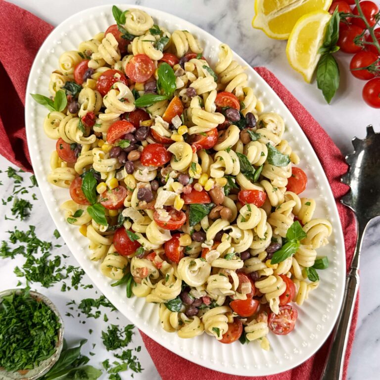 A oval white plate with Pasta and cowboy caviar and Tomoatoes