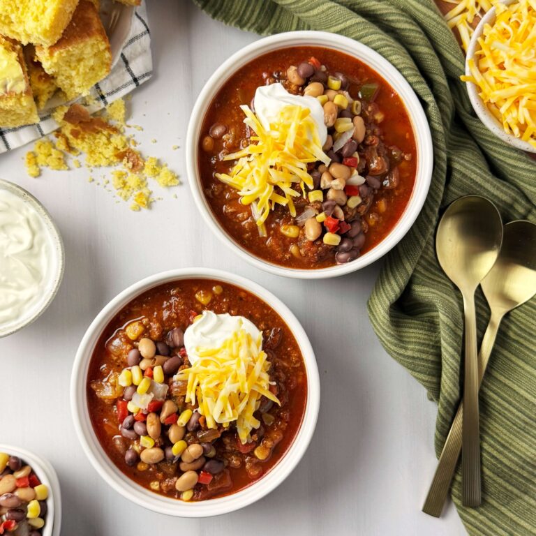 Two white bowls of chili. on a counter top.
