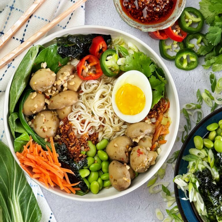 A dinner bowl filled with Mushroom and Vegetable Ramen Inspired soup on a table setting.