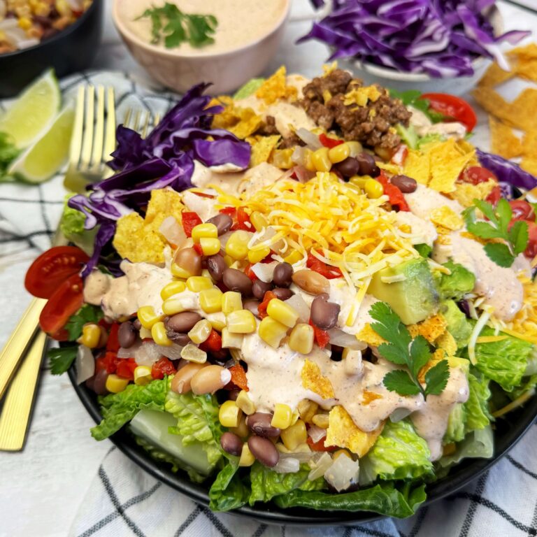 A black dinner bowl of Taco Salad with Cowboys Caviar and Creamy Salsa Ranch Dressing