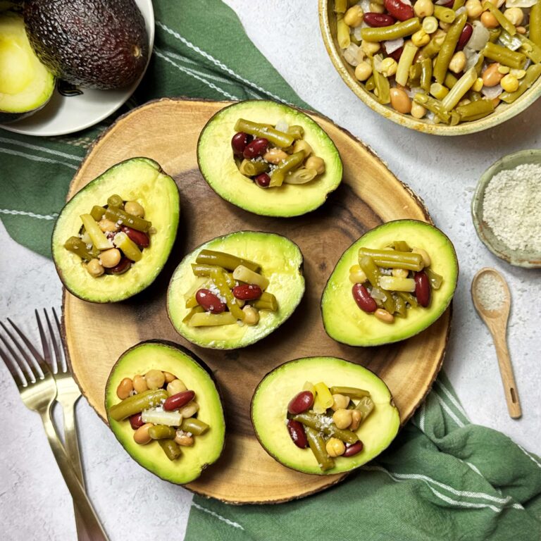 a wooden plater with stuffed avocados with five Bean salad